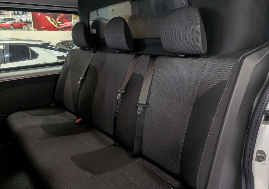 Vue intérieure côté droit des sièges arrière en tissu gris foncé du Renault Trafic Cabine Approfondie blanc minéral 2023.