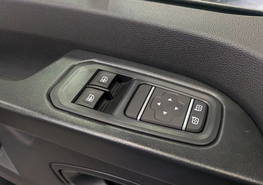 Panneau de commandes des vitres et rétroviseurs électriques sur la portière côté gauche d'un Renault Trafic blanc 2023.
