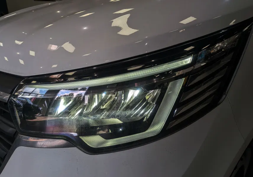 Gros plan sur le phare avant droit du Renault Trafic Cabine Approfondie blanc minéral 2023, avec éclairage LED distinctif.