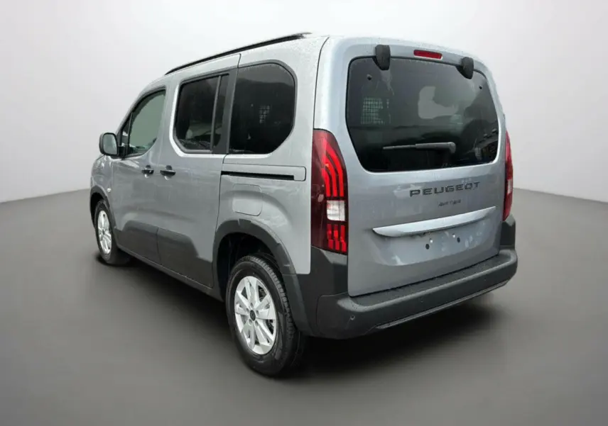 Vue 3/4 arrière droit d’un Peugeot Rifter gris artense avec vitres surteintées et grille de séparation dans le coffre.