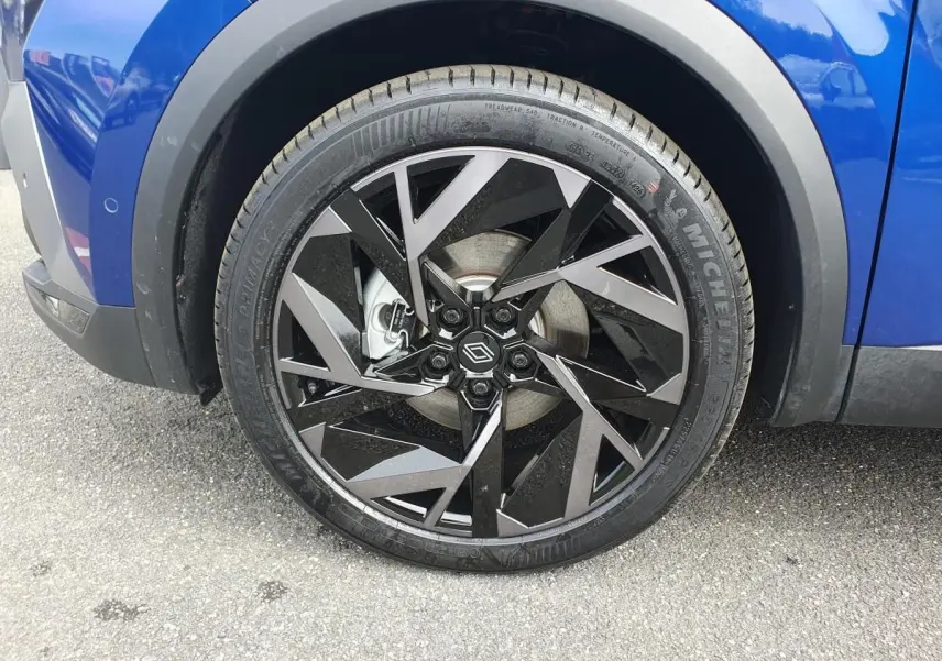 Gros plan sur la jante aluminium 19 pouces Elixir noire et argent du Renault Captur bleu Iron, côté arrière droit.