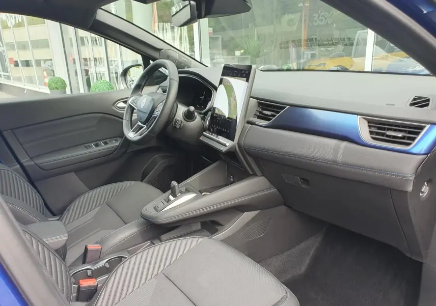 Intérieur avant droit du Renault Captur bleu Iron 2026, avec tableau de bord numérique et écran tactile vertical.