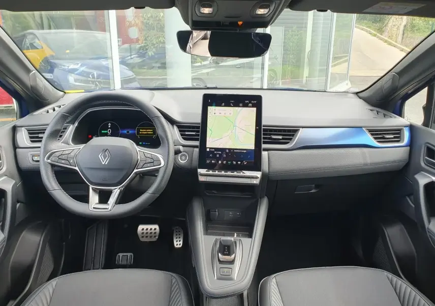 Vue intérieure avant du Renault Captur bleu Iron 2026, tableau de bord avec écran tactile vertical et volant multifonction.