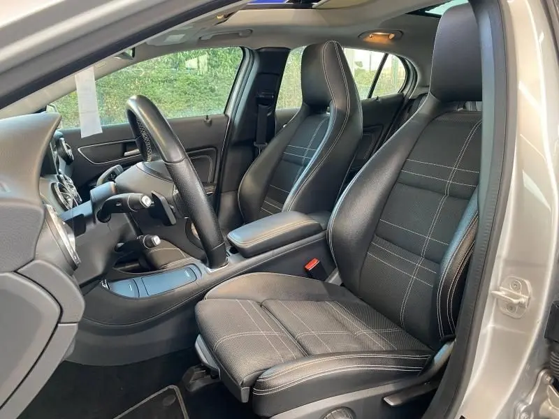 Vue intérieure côté conducteur du Mercedes GLA 200 Sensation 2017 avec sièges sport noirs et coutures blanches.
