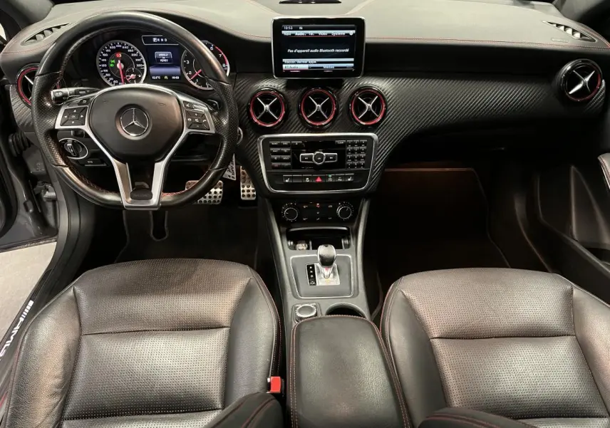 Intérieur de Mercedes Classe A 45 AMG 2015, vue avant centrée sur tableau de bord en carbone et sièges cuir noirs.