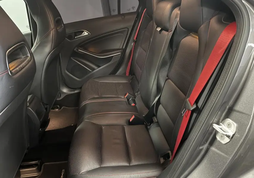 Vue intérieure côté droit des sièges arrière noirs avec ceintures rouges d'une Mercedes Classe A 45 AMG gris métallisé 2015.