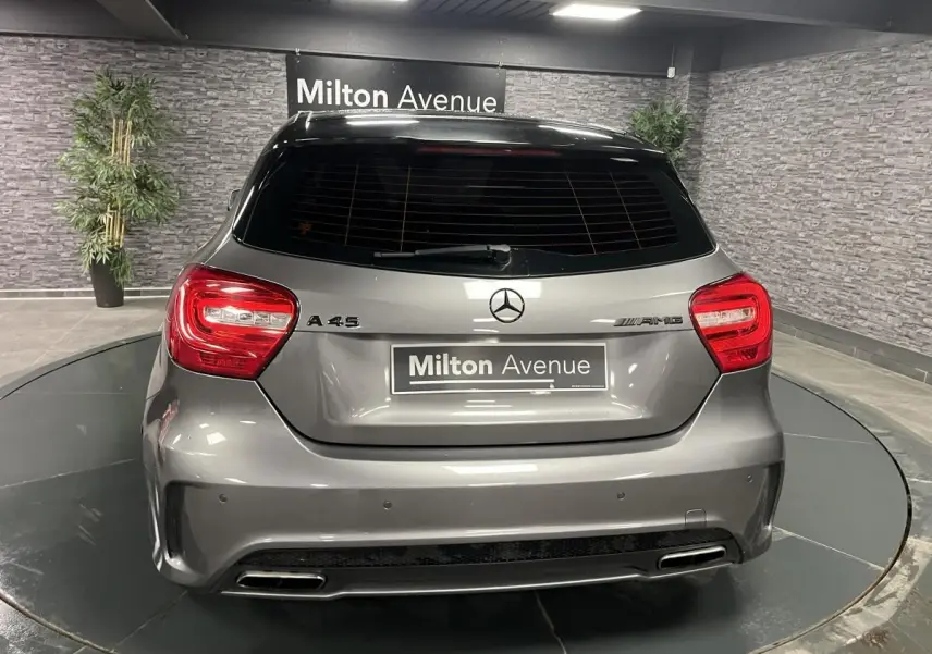 Vue arrière d'une Mercedes Classe A 45 AMG grise métallisée avec feux rouges et double sortie d'échappement chromée.