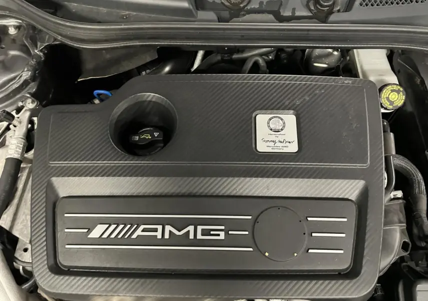 Vue plongeante sur le moteur AMG noir texturé de la Mercedes Classe A 45 AMG 2015 avec plaque constructeur visible.