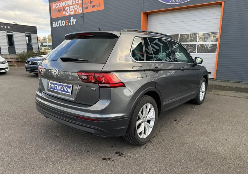 Volkswagen Tiguan gris Indium vu en 3/4 arrière droit, avec jantes alliage et vitres arrière surteintées.