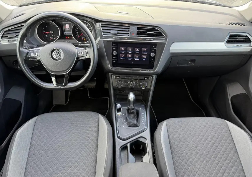 Vue intérieure avant du Volkswagen Tiguan 2018, tableau de bord et console centrale avec écran tactile et volant cuir multifonctions.