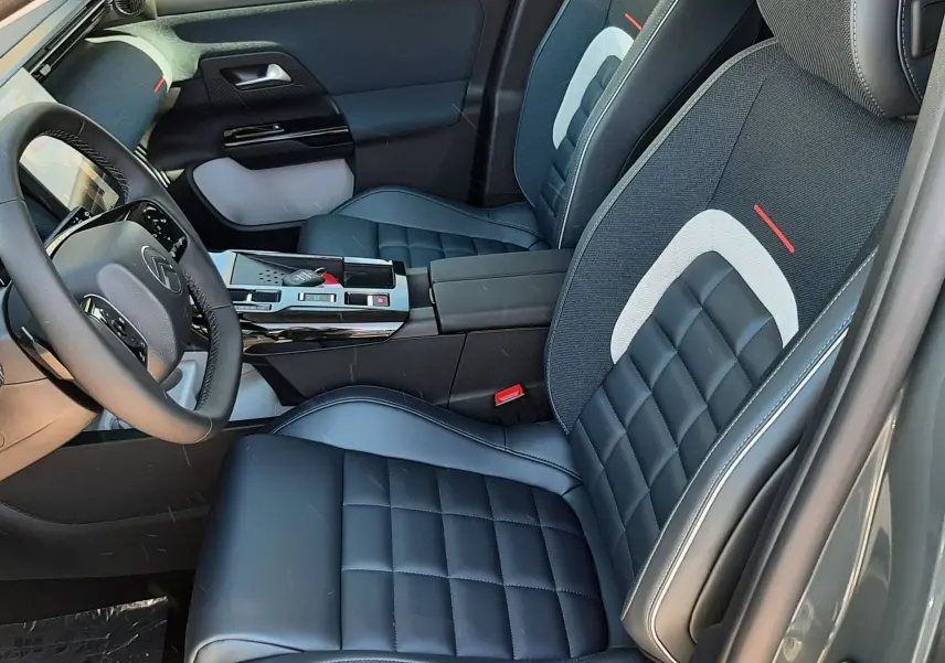 Vue intérieure côté conducteur du Citroën C5 Aircross 2026, sièges noirs avec détails gris et rouge, console centrale moderne.