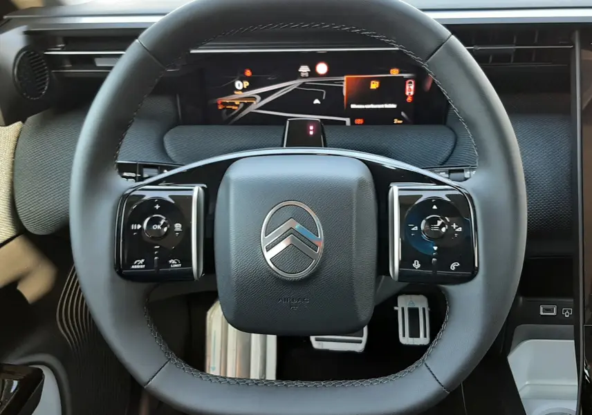 Vue rapprochée du volant noir du Citroën C5 Aircross 2026 avec tableau de bord numérique et commandes intégrées.