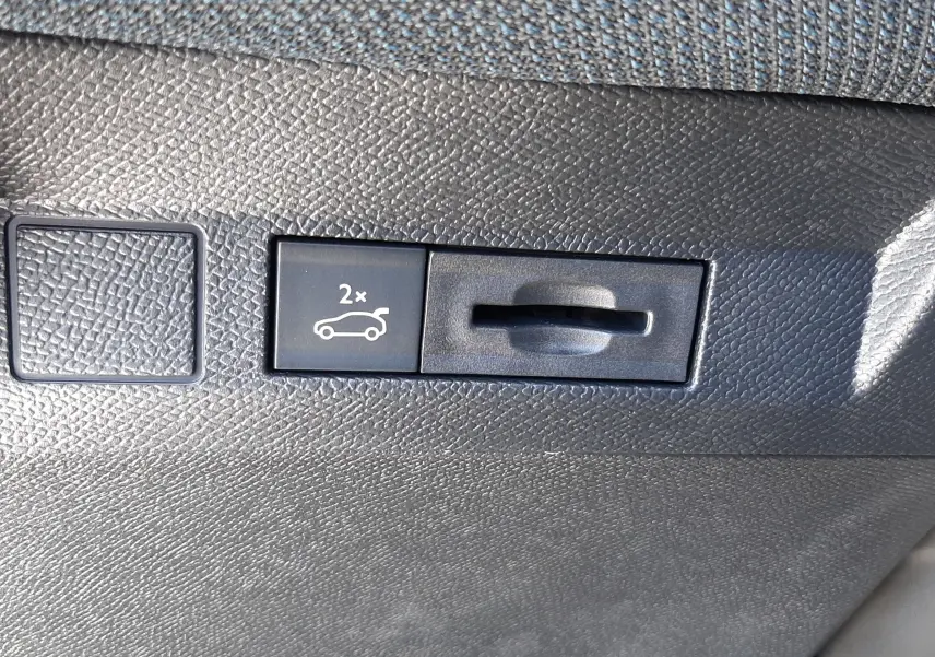 Gros plan sur le bouton d'ouverture électrique du hayon, intérieur noir texturé du Citroën C5 Aircross 2026.