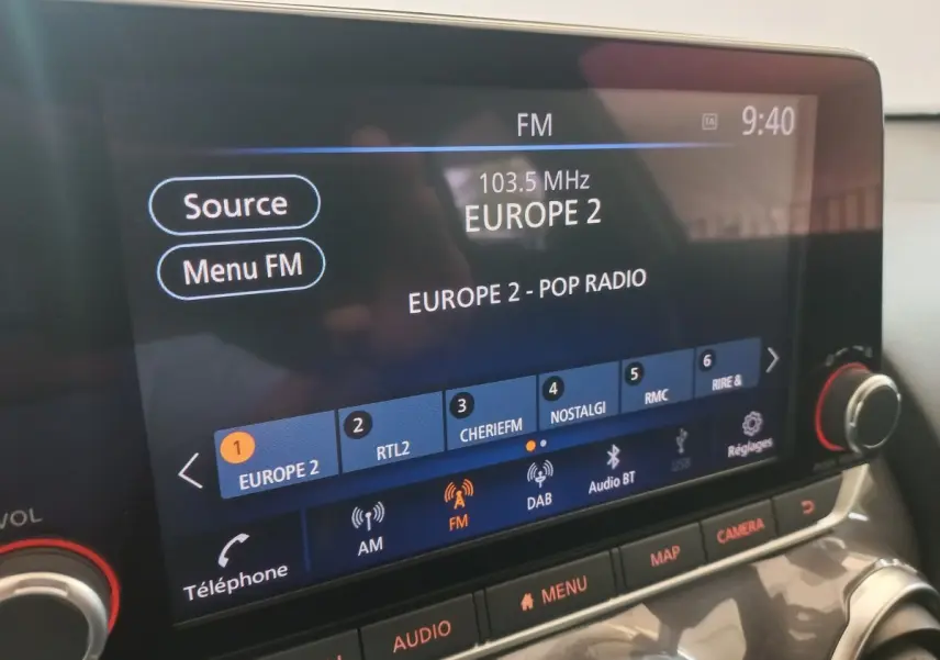 Écran tactile central de la Nissan Juke Hybrid 2023 affichant la radio FM Europe 2, avec commandes audio visibles.