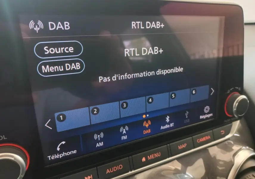 Écran tactile central du Nissan Juke Hybrid 143 Business+ 2023, affichant la radio DAB, vue rapprochée intérieure.