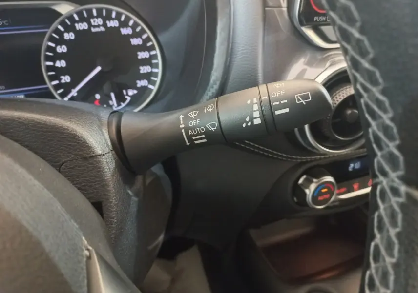 Gros plan sur la manette d’essuie-glace du tableau de bord du Nissan Juke Hybrid 143 Business+ gris foncé, intérieur noir.