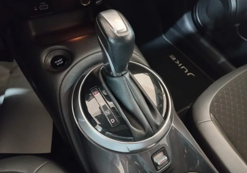 Gros plan sur la commande de boîte automatique et bouton start/stop dans l’habitacle gris foncé du Nissan Juke Hybrid 2023.