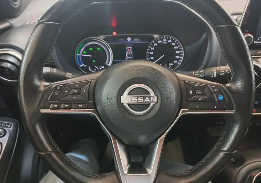 Vue rapprochée du volant cuir et alu multifonctions du Nissan Juke Hybrid 143 Business+ 2023 avec tableau de bord numérique.