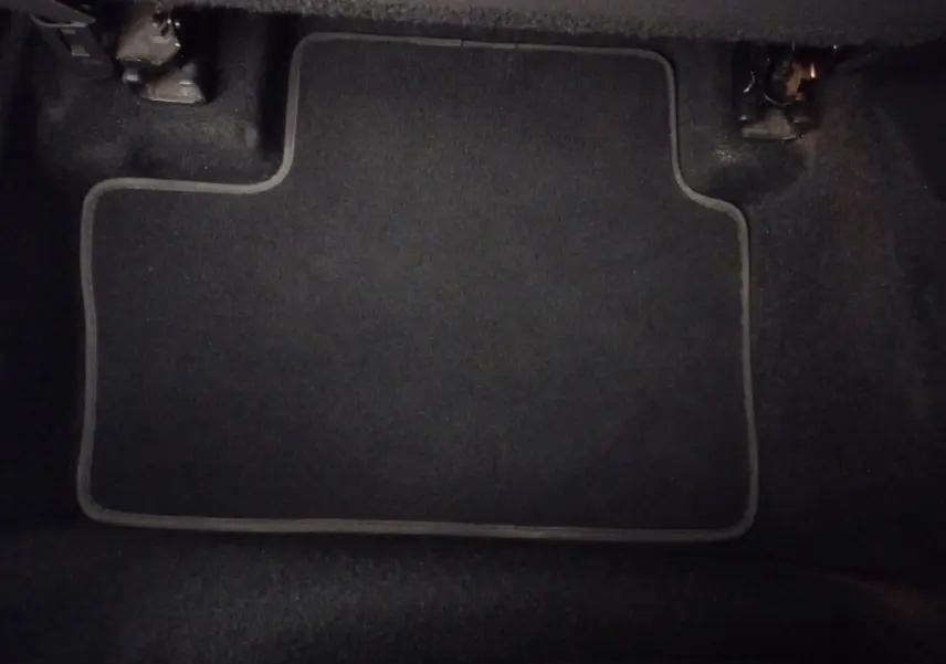 Vue intérieure du coffre du Nissan Juke Hybrid 143 Business+ 2023, tapis de sol gris foncé visible au sol.