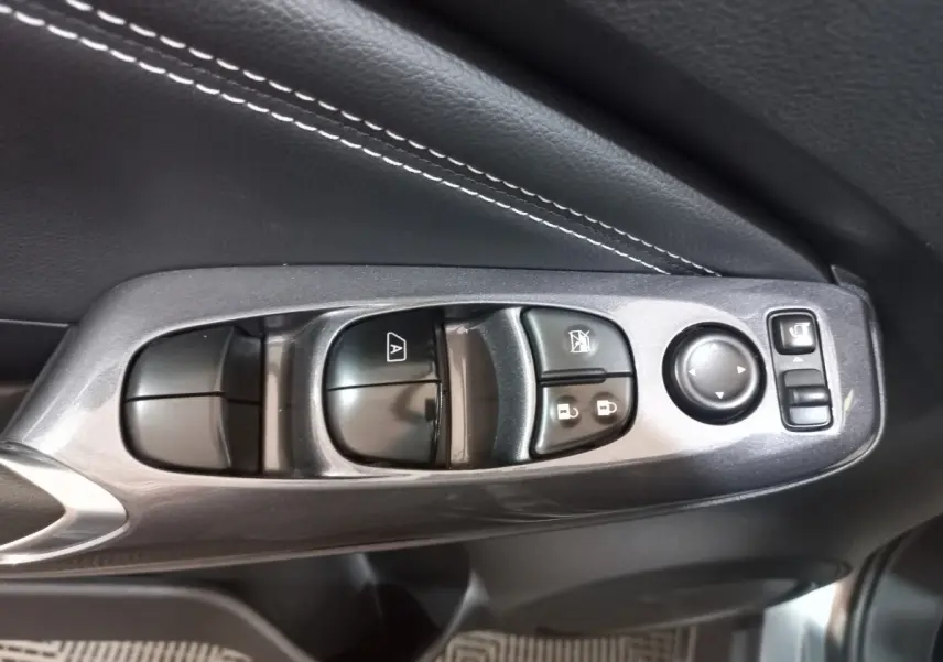 Gros plan sur les commandes de lève-vitres et rétroviseurs côté conducteur du Nissan Juke Hybrid 143 Business+ gris foncé.