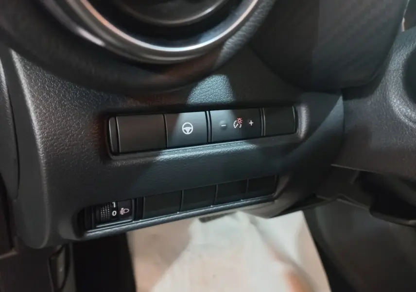 Détail intérieur du tableau de bord du Nissan Juke Hybrid 143 Business+ 2023, montrant les commandes de réglage du volant.