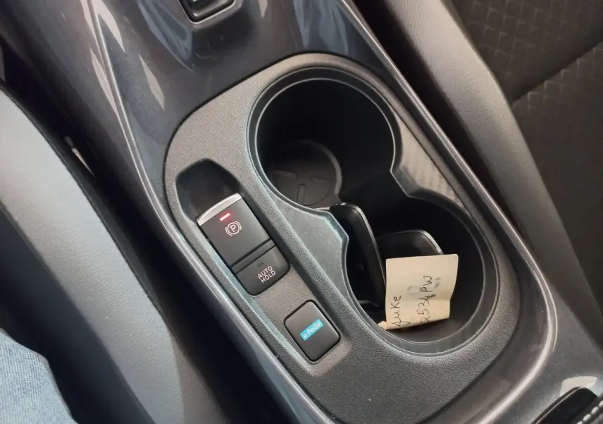 Gros plan intérieur sur la console centrale noire du Nissan Juke Hybrid 143 Business+ avec boutons e-Pedal et frein à main électrique.