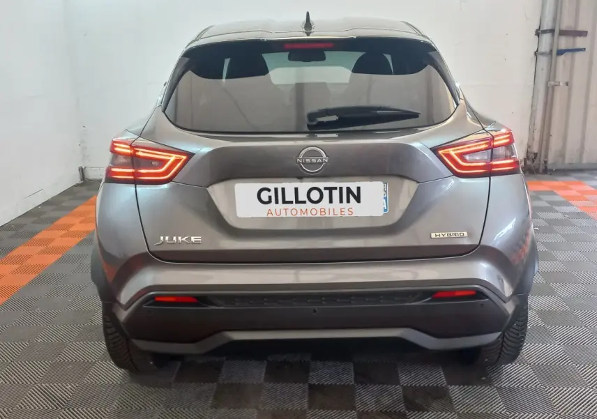 Vue arrière d'un Nissan Juke Hybrid gris foncé avec feux LED allumés dans un garage fermé.