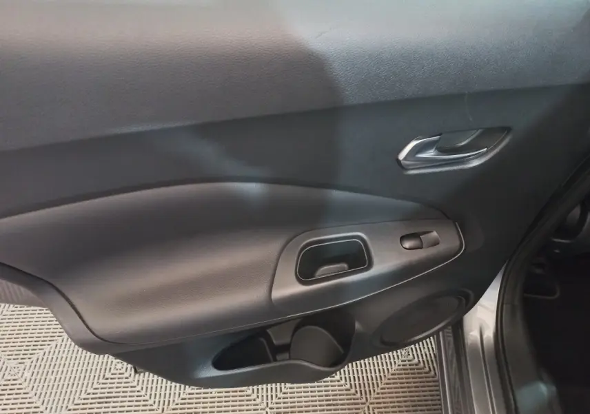 Vue rapprochée de la porte avant droite intérieure du Nissan Juke Hybrid 143 Business+ gris foncé, avec poignée et commande de vitre.