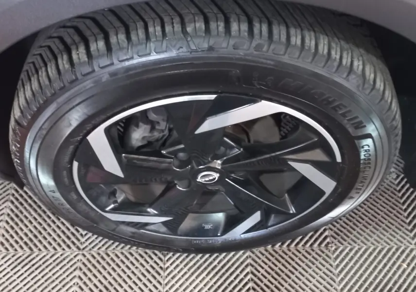 Gros plan sur la roue avant droite du Nissan Juke Hybrid 143 Business+ avec jante noire et inserts argentés.