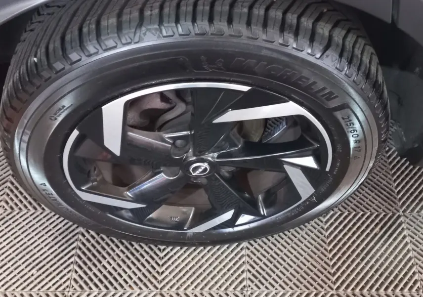 Gros plan sur la jante noire et argentée du Nissan Juke Hybrid 143 Business+ 2023 avec pneu Michelin.