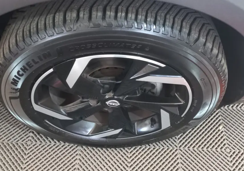 Gros plan sur la roue avant droite du Nissan Juke Hybrid 143 Business+ gris foncé avec jante noire et argentée.