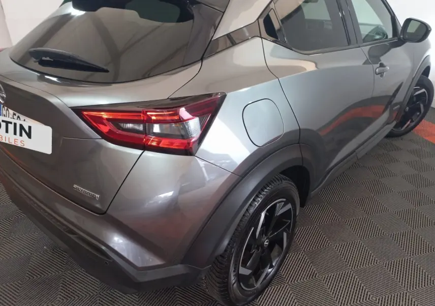Vue 3/4 arrière droit du Nissan Juke Hybrid 143 Business+ gris foncé avec jantes noires et feux LED distinctifs.