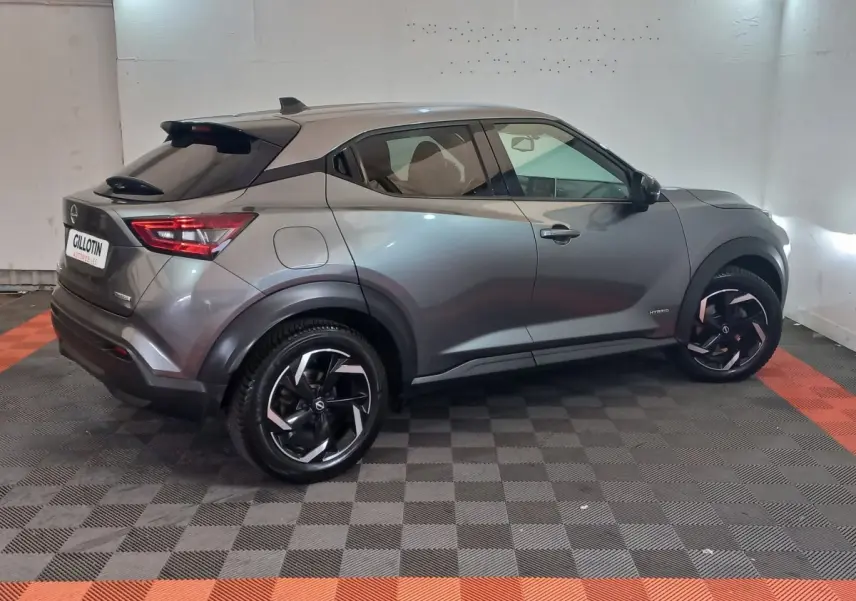 Nissan Juke Hybrid gris foncé vu de profil côté droit, avec jantes noires et détails modernes au niveau des ailes.