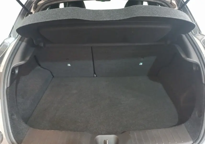 Coffre ouvert du Nissan Juke Hybrid 143 Business+ gris foncé, vue arrière montrant l’espace de chargement vide.