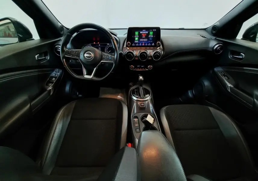 Vue intérieure avant du Nissan Juke Hybrid 143 Business+ 2023, tableau de bord et volant cuir alu noir, console centrale avec écran tactile.