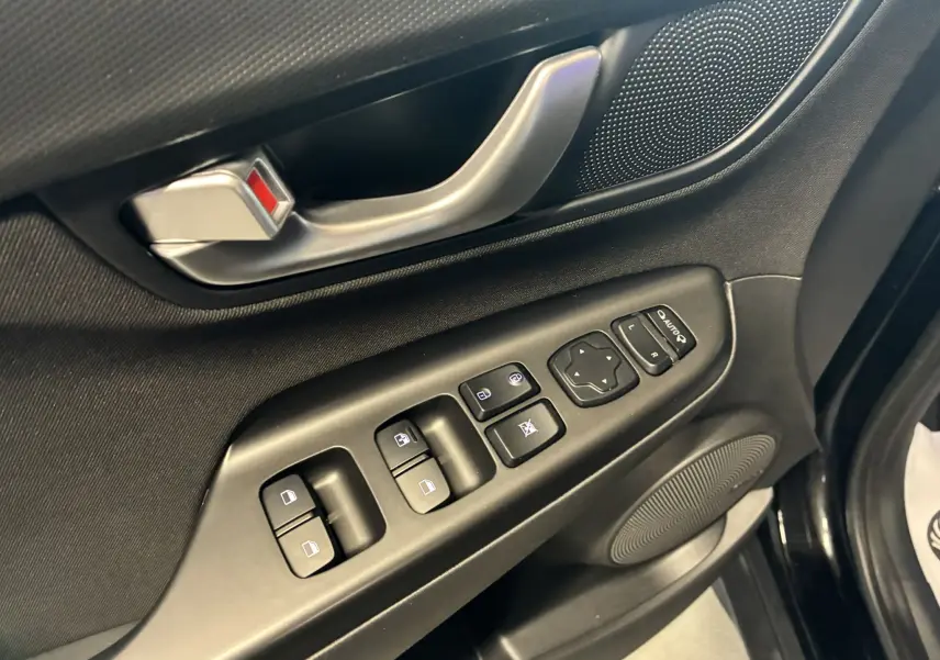 Gros plan sur la porte côté conducteur du Hyundai Kona noir 2023, montrant les commandes électriques et la poignée intérieure argentée.