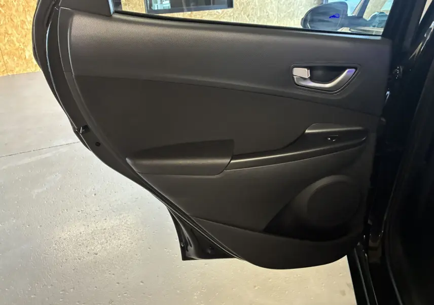 Porte arrière côté droit noire du Hyundai Kona 1.6 GDI 140 Creative 2023, intérieur tissu noir avec commande de fenêtre.
