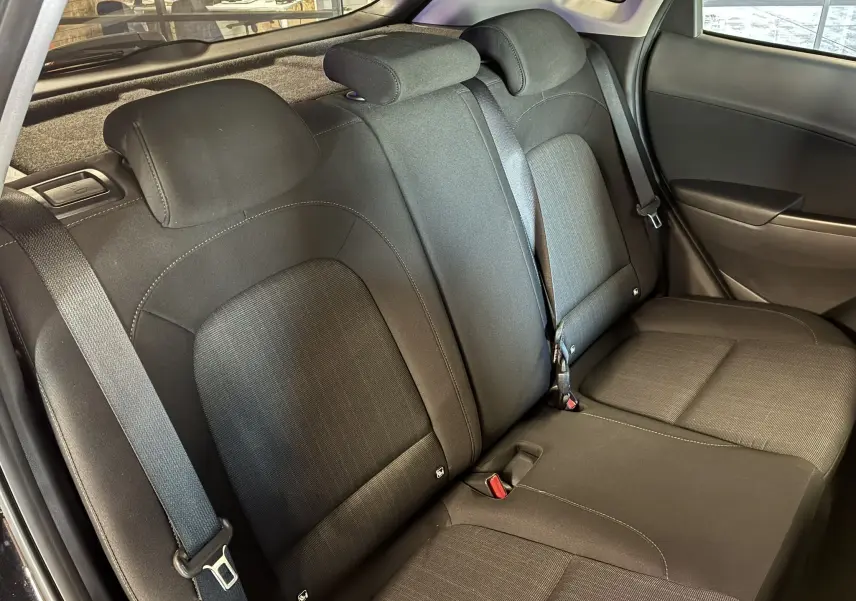 Vue intérieure du siège arrière côté droit du Hyundai Kona 2023 noir, avec ceintures de sécurité et appuie-têtes en tissu noir.
