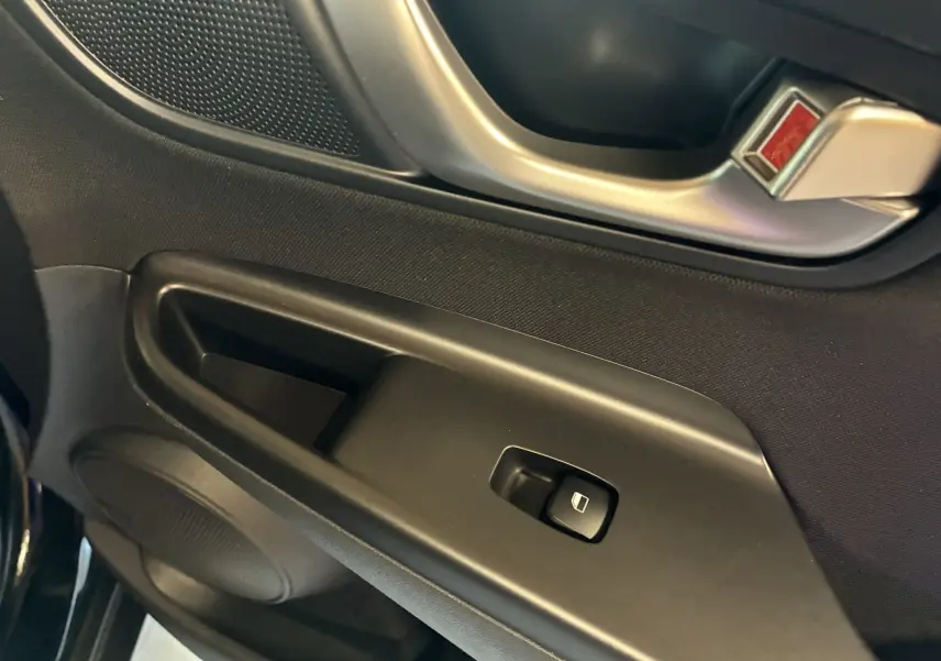 Gros plan sur la poignée intérieure et le bouton de lève-vitre côté gauche d'une Hyundai Kona noire 2023.