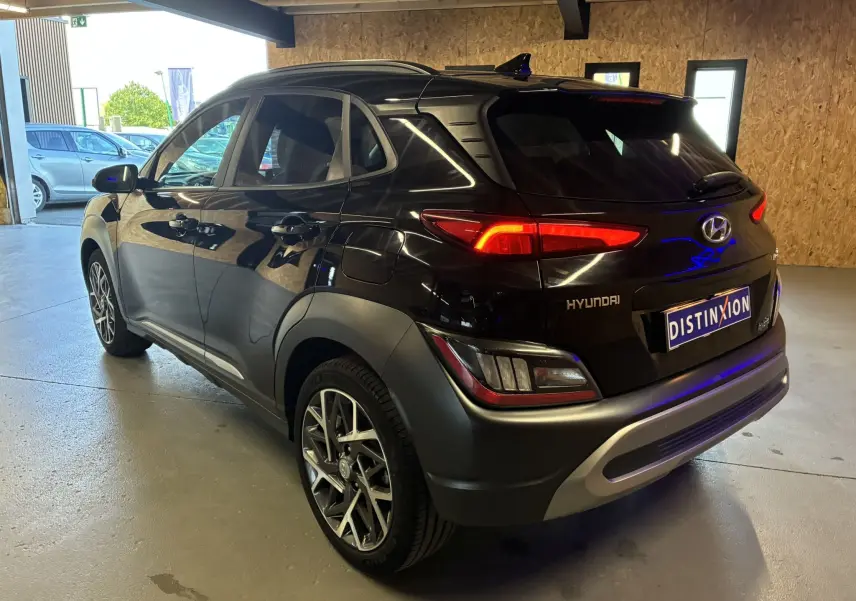 Vue 3/4 arrière droite du Hyundai Kona noir 2023 avec feux arrière allumés et jantes alliage distinctives.