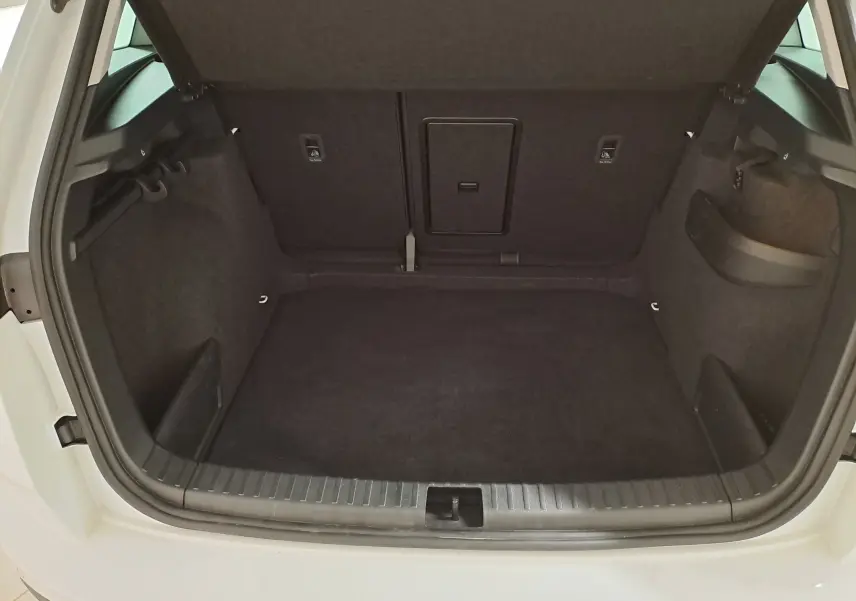 Coffre ouvert vu de l'arrière d'un Skoda Karoq blanc Lune 2025, montrant un espace de chargement propre et spacieux.