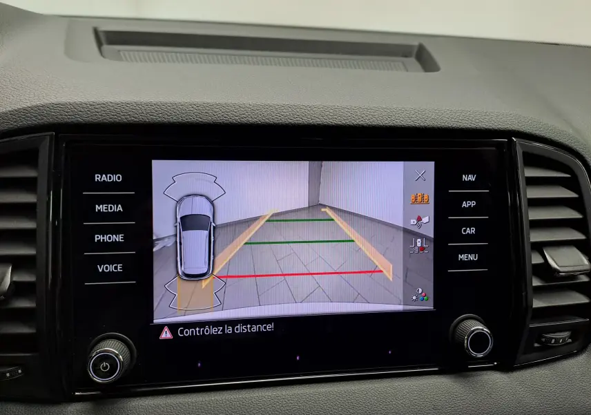 Écran multimédia du Skoda Karoq blanc Lune montrant la caméra de recul avec guidage de trajectoire et alertes de distance.