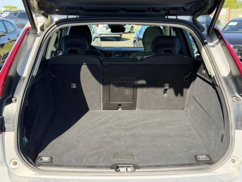 Coffre ouvert vu de l'arrière d'un Volvo XC60 gris, montrant l'espace de chargement et les sièges arrière.