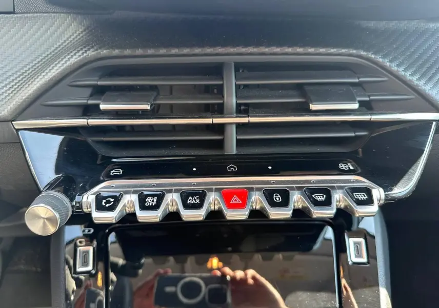 Vue rapprochée du tableau de bord de la Peugeot 208 2025, boutons de commande et aérateurs noirs avec finition chrome.