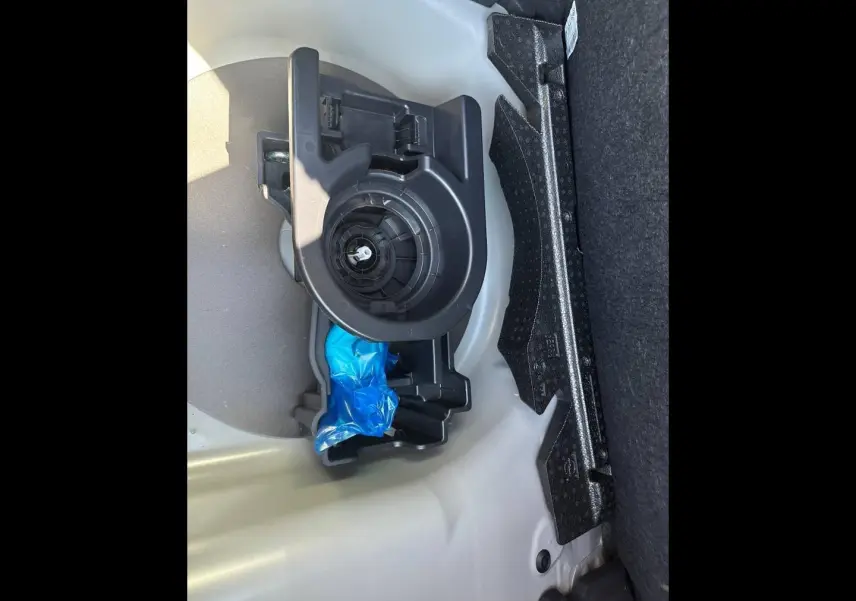 Gros plan sur le rangement sous le plancher du coffre de la Peugeot 208 gris Selenium, montrant un support plastique noir.