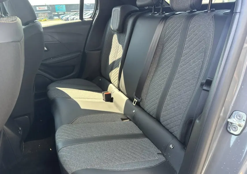 Vue intérieure côté arrière droit montrant la banquette tissu gris avec appuie-têtes et ceintures de sécurité de la Peugeot 208 2025.