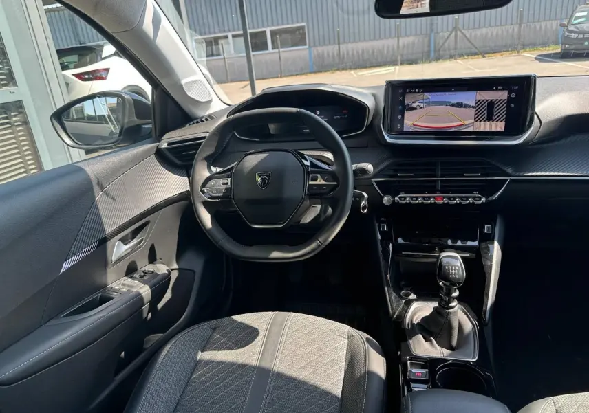 Vue intérieure avant de la Peugeot 208 1.2 100ch S&S Allure avec tableau de bord noir et écran tactile central.