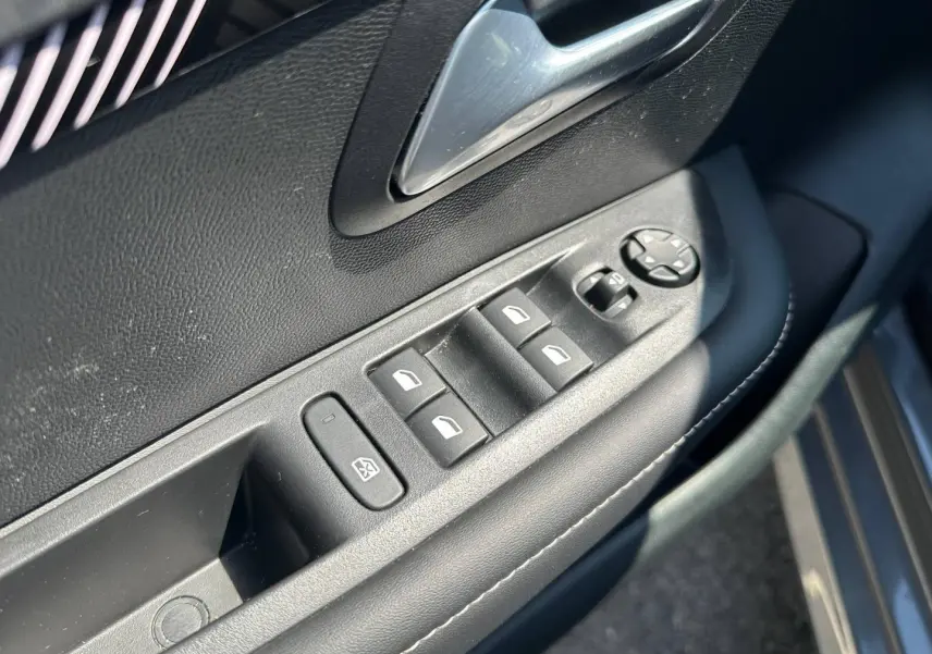 Commande des vitres électriques et rétroviseurs sur la porte côté gauche d'une Peugeot 208 gris Selenium 2025.