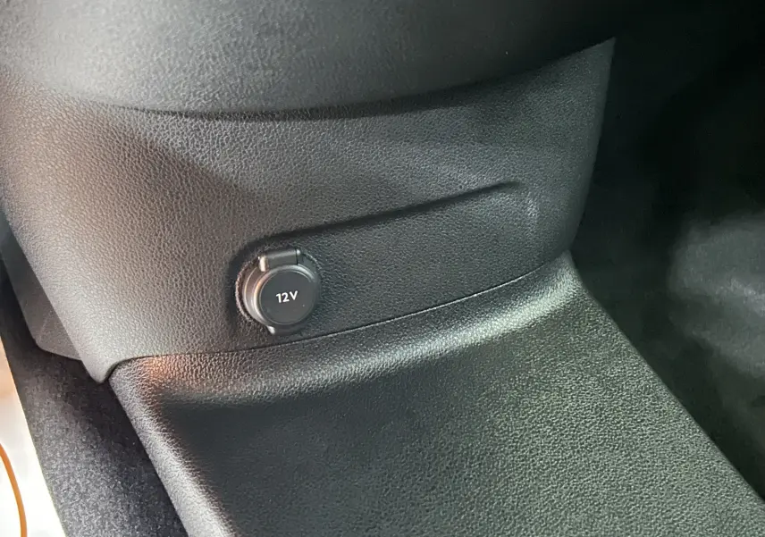Prise 12V noire intégrée dans la console centrale du Citroën Berlingo Multispace gris, vue intérieure rapprochée.