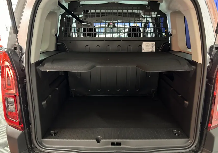 Vue arrière du coffre ouvert du Citroën Berlingo Multispace gris Artense avec séparation grillagée et tablette de rangement.